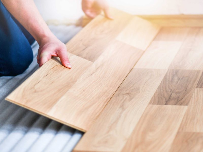 Worker hands installing timber laminate floor. Wooden floors house renovation with measure items.